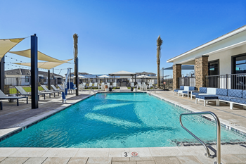 A large outdoor swimming pool with a metal ladder and a yellow umbrella.